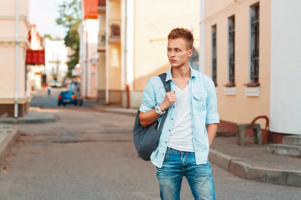 Jovem homem bonito com uma mochila em uma camisa jeans e roupas de jeans viajando . — Fotografia de Stock