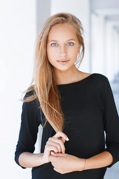 Beautiful woman with blue eyes in a black shirt on a light background — Zdjęcie stockowe