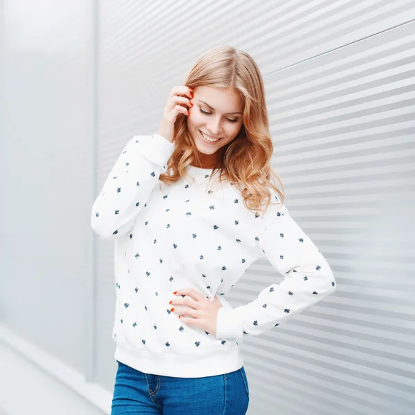 Portrait of a pretty smiling woman posing in front of modern metallic wall background — Zdjęcie stockowe