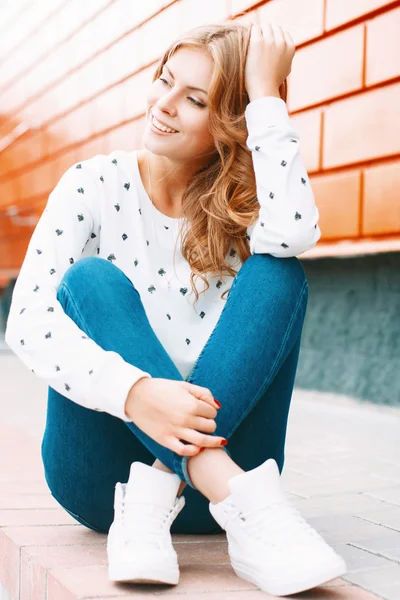 Красива стильна дівчина сидить біля барвистої стіни — стокове фото