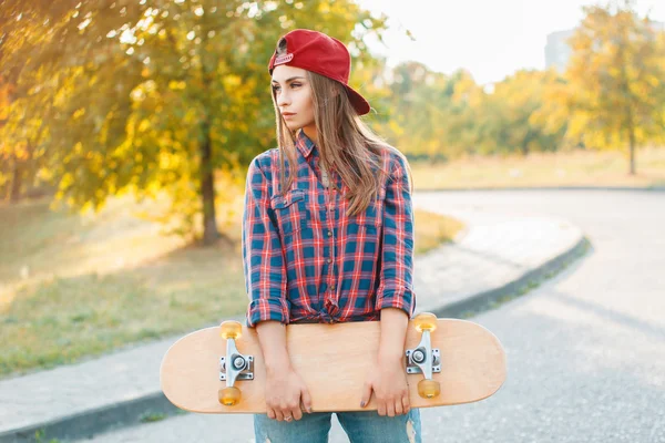Όμορφη και μόδα νεαρή γυναίκα ποζάρουν με ένα skateboard — Φωτογραφία Αρχείου