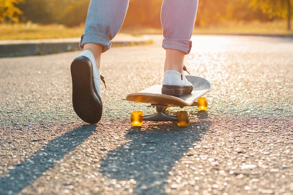 Femme skateboard au lever du soleil. Jambes sur le skateboard, passe au succès — Photo