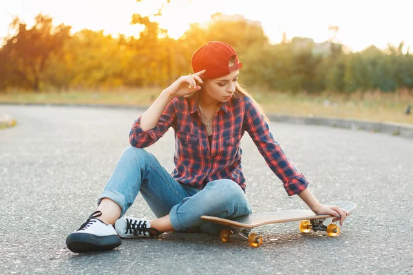 Woman with skateboard at sunset. — Stock fotografie