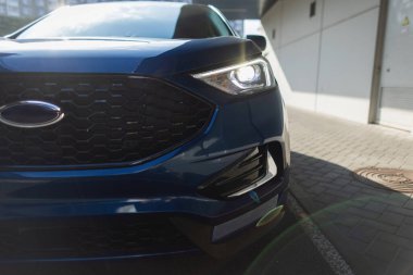 Çağdaş mavi SUV aracı ön farları ve ızgara detaylarıyla yakın plan.