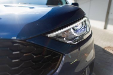 Şehir sokaklarında gün ışığında parlayan SUV 'yi gösteren modern ulaşım konsepti. Mavi geçiş aracı otoparkta izole edilmiş ve arkasında bina duvarı var..