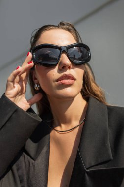 Moda mankeni şık, çekici bir kadın. Güneş ışınlarında sokakta güneş gözlüğü takıyor. Şehirde çok ateşli bir kadın var.