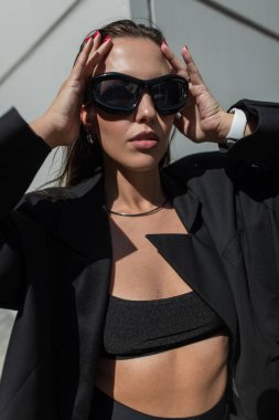 Şık siyah elbiseli, şehirde güneş gözlüklü, göz kamaştırıcı, şık bir kadın modeli. Güzel bayan. Güzellik ve tarz
