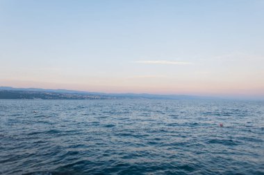 Açık deniz, yumuşak dalgalar ve alacakaranlıkta pastel tonlu gökyüzü. Seyahat, yaz ve huzur konseptleri için huzurlu bir manzara. Hırvatistan, Opatija. Yaz tatili