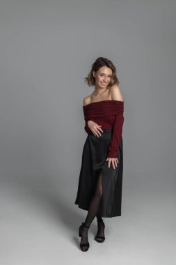 Moda mankeni, kırmızı omuz süveteri ve stüdyoda siyah etek giyen güzel, zarif bir kadın. Kadın portresi. Güzel bayan.