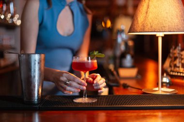 Güzel barmen kız barın tezgahında naneli alkollü kokteyl hazırlıyor.