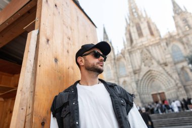 Yakışıklı gezgin, güneş gözlüklü, kot yelekli havalı adam.