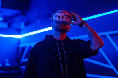 Sanal dünyada sanal gözlüklü siber adam kulaklık kullanıyor.