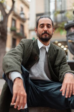 Barcelona 'da sokakta oturan yeşil ceketli yakışıklı, modaya uygun bir İspanyol.