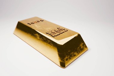 Altın çubuk. tek büyük altın külçe külçe külçe (1000g, 999.9 altın) temiz beyaz bir yüzeyde bir açıyla görülür. Yatırım, zenginlik, rezerv, güvenlik ve bankacılık varlıklarını temsil eder.