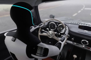 Al antika bir araba kullanıyor. Klasik bir spor arabanın direksiyonunda parlayan ışığı olan robot. Teknoloji nostaljiyle buluşuyor. Geleceğin otonom sürücüsü. Otonom sürüş konsepti. Gelecekçi yapay zeka robotu