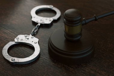 Karanlık bir masada metal kelepçeli tahtadan yargıç tokmağı. Ceza hukuku, tutuklama, ceza ve adalet sistemi kavramı. Mahkeme salonu ve suçla ilgili konular için mesleki hukuki geçmiş.