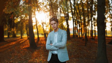 Genç yakışıklı bir şık ceket ve gömlek ayakta batımında Park.