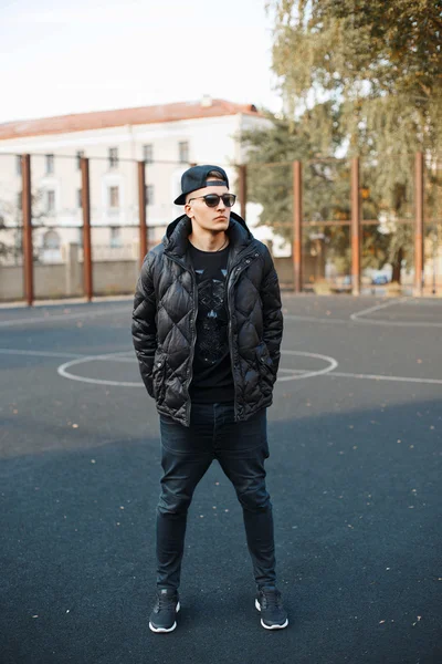 Pohledný mladík v černém oblečení a zimní bundy — Stock fotografie