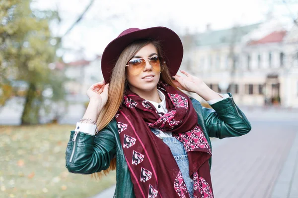 Bella donna elegante con un cappello, occhiali da sole e giacca su uno sfondo di città di autunno — Foto Stock