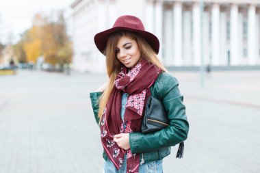 Beautiful girl smiling in a fashionable hat and scarf on the background of the city