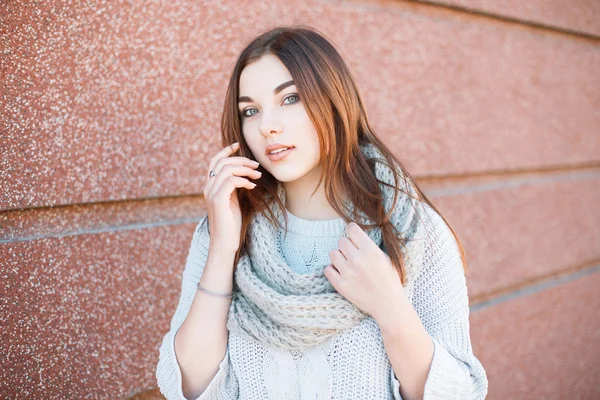 Красивая девушка в свитере стоит у стены — стоковое фото