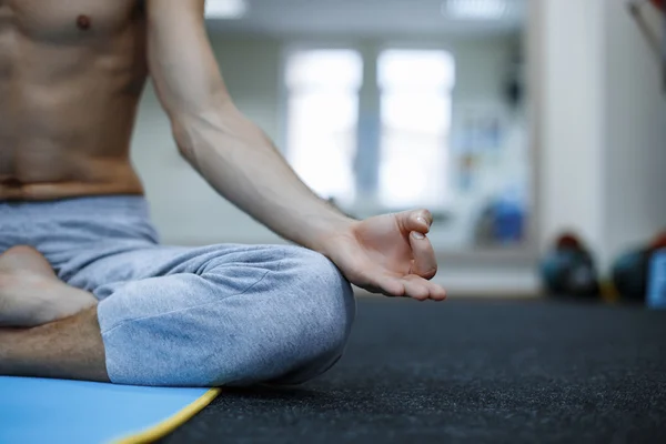 Young man in meditation on the background of the gym — Stock Photo, Image