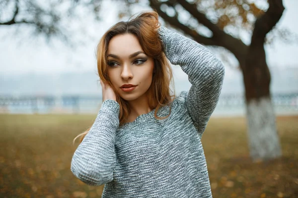 Menina bonita nova em uma camisola de malha em um dia nebuloso de outono — Fotografia de Stock