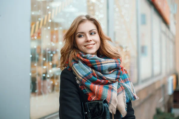 Cute woman in warm clothes on the background of the store with lights