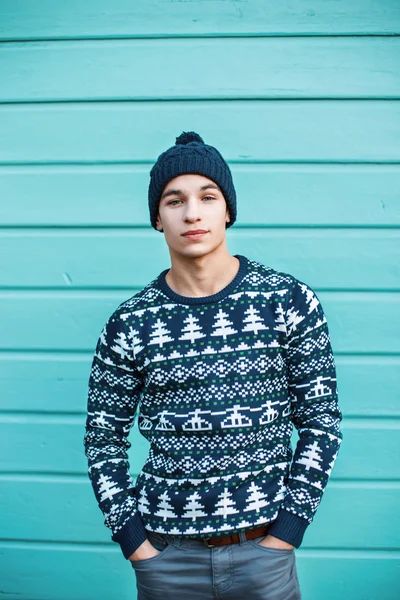 Young handsome hipster man in stylish knitted clothes against a background of colorful wooden wall — Stock Fotó