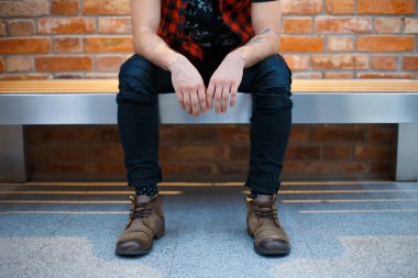 Young stylish guy sitting on the bench in a supermarket. Man waiting for his girlfriend.