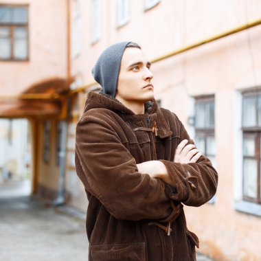 Şapkanı ve Paltonu gecekondu avlusunda duran yakışıklı genç adam