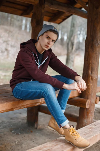 Young handsome man in a hat and leather boots in a forest — Stock Photo, Image