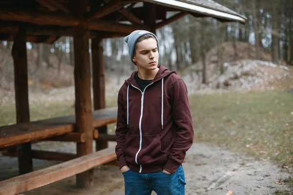 Fiatal stílusos srác a kalapban, a háttérben az erdő — Stock Fotó