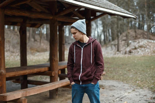 Young handsome guy in a knitted hat in the park — Stock Photo, Image