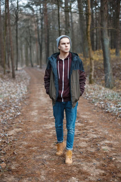 Jovem homem bonito caminhando ao longo da floresta de outono — Fotografia de Stock