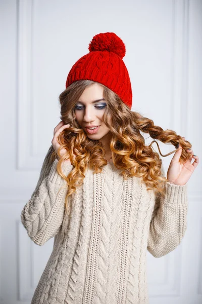 Chica joven con el pelo rizado en un sombrero de punto rojo y un suéter caliente —  Fotos de Stock