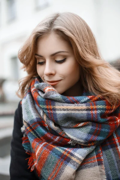 Cute young woman in trendy knitted scarf and black coat in autumn day — Stock Photo, Image