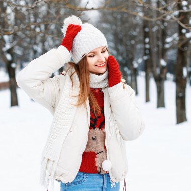 Young stylish girl in knitted vintage clothing resting on a snowy background
