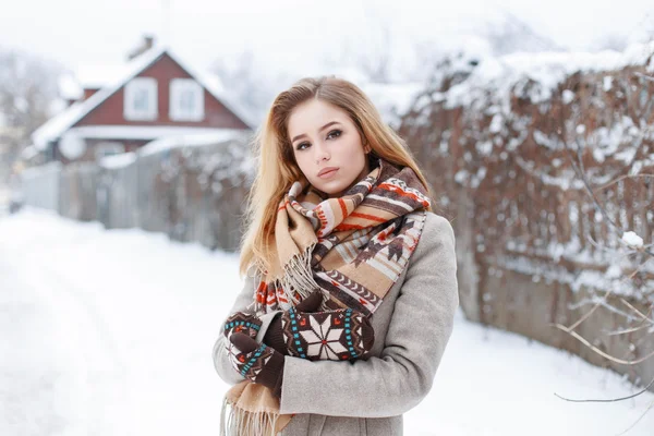 Beautiful young girl in stylish winter clothes walking near the house in winter day — 图库照片