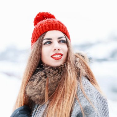 Happy portrait of a beautiful pretty woman with red lips and a smile in winter snowy day