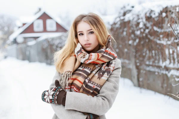 Beautiful woman with a vintage scarf and knitted mittens standing in the village near the fence — Stock Fotó