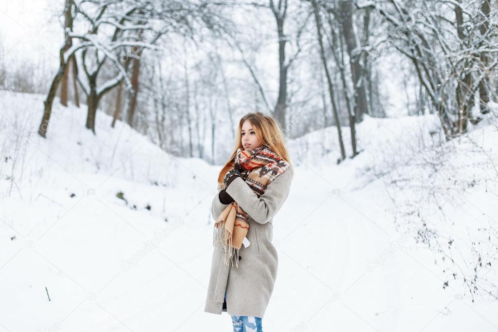 Beautiful woman standing in a winter park near a tree in a stylish vintage clothing.