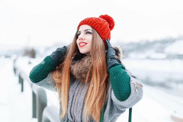 Happy beautiful girl smiling and looking up in stylish winter clothes on a background of a snowy landscape — ストック写真