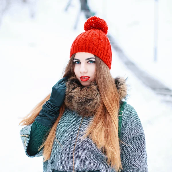 Young beautiful girl with a red hat and coat in winter snowy day — 스톡 사진