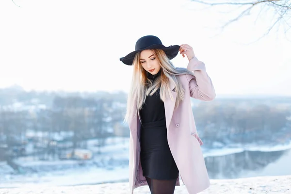 Young beautiful girl in hat and coat on a background of a winter landscape — Stok fotoğraf