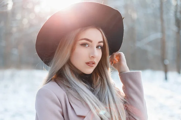 Porträt eines jungen schönen Mädchens mit schwarzem Hut an einem Wintertag bei Sonnenuntergang — Stockfoto