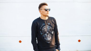 Yakışıklı genç hipster adam bir kafatası ve güneş gözlüğü ile siyah şık giyim