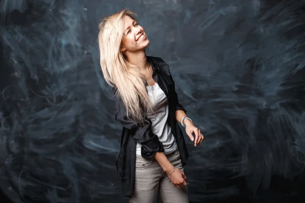 Positive cute cheerful girl with blond hair laughing on a dark background — Zdjęcie stockowe