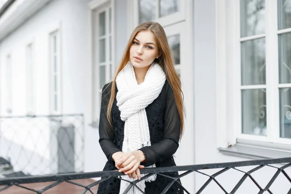 Beautiful girl with a white knitted warm scarf and a black dress — Stockfoto