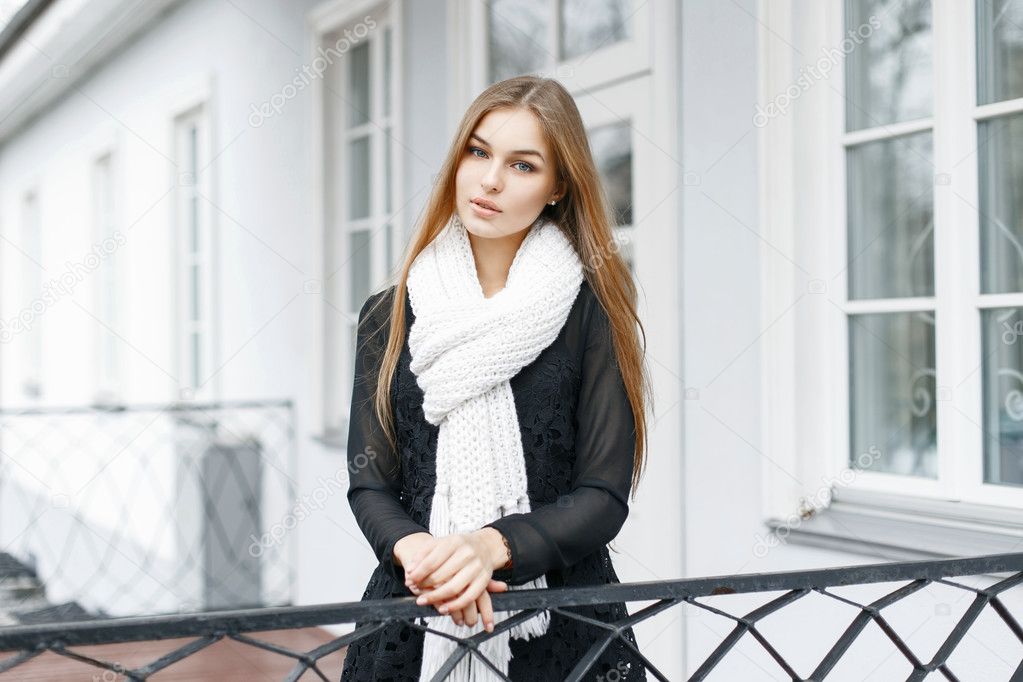 Beautiful girl with a white knitted warm scarf and a black dress